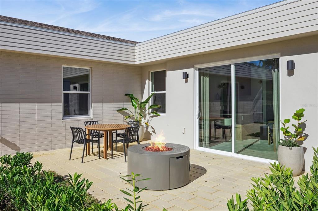 A patio features a circular fire pit, a small dining set, and sliding glass doors — 450 SKYFIELD COURT, LADY LAKE, FL
