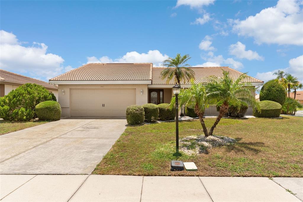 A single-story house with a beige stucco exterior, a tile roof, and a two-car garage — 701 BALTUSROL WAY, SUN CITY CENTER, FL