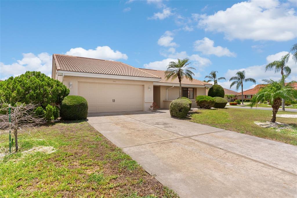 A single-story house with a beige exterior, a two-car garage, and a concrete driveway — 701 BALTUSROL WAY, SUN CITY CENTER, FL