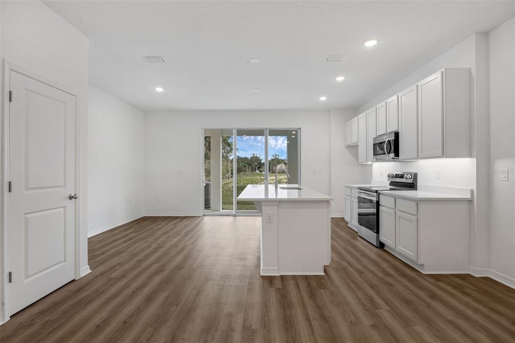 A bright kitchen with white cabinets, a central island, and wood-look flooring — 1156 CYPRESS ELM DRIVE, DELAND, FL