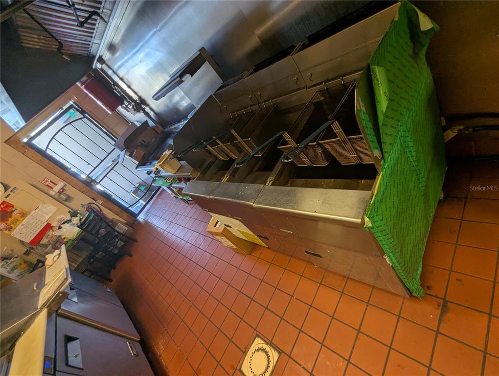 A commercial kitchen features a multi-vat deep fryer and red tiled flooring — 2430 US HIGHWAY 27 UNIT 380, CLERMONT, FL