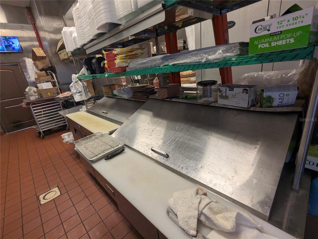 A commercial kitchen prep area features stainless steel counters, shelving, and tiled flooring — 2430 US HIGHWAY 27 UNIT 380, CLERMONT, FL