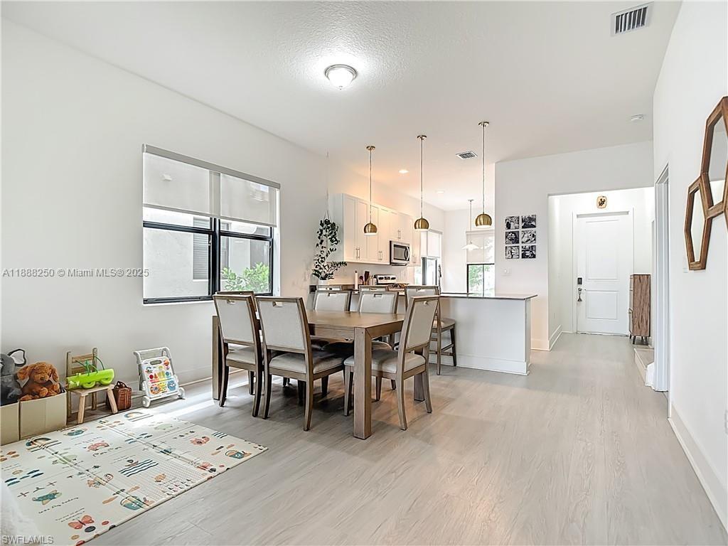 A dining area with a wooden table and chairs sits adjacent to an open kitchen — 5696 Argento Dr, Ave Maria FL 34142, AVE MARIA, FL