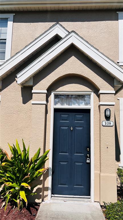 A blue front door with a transom window is centered under a gabled roofline — 9165 LEE VISTA BOULEVARD UNIT 108, ORLANDO, FL