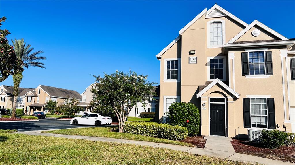 A tan multi-story residential building with black shutters and a white front door — 9165 LEE VISTA BOULEVARD UNIT 108, ORLANDO, FL