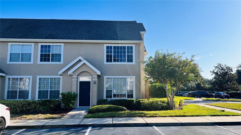 A two-story tan townhouse with a dark front door and a small tree out front — 9165 LEE VISTA BOULEVARD UNIT 108, ORLANDO, FL