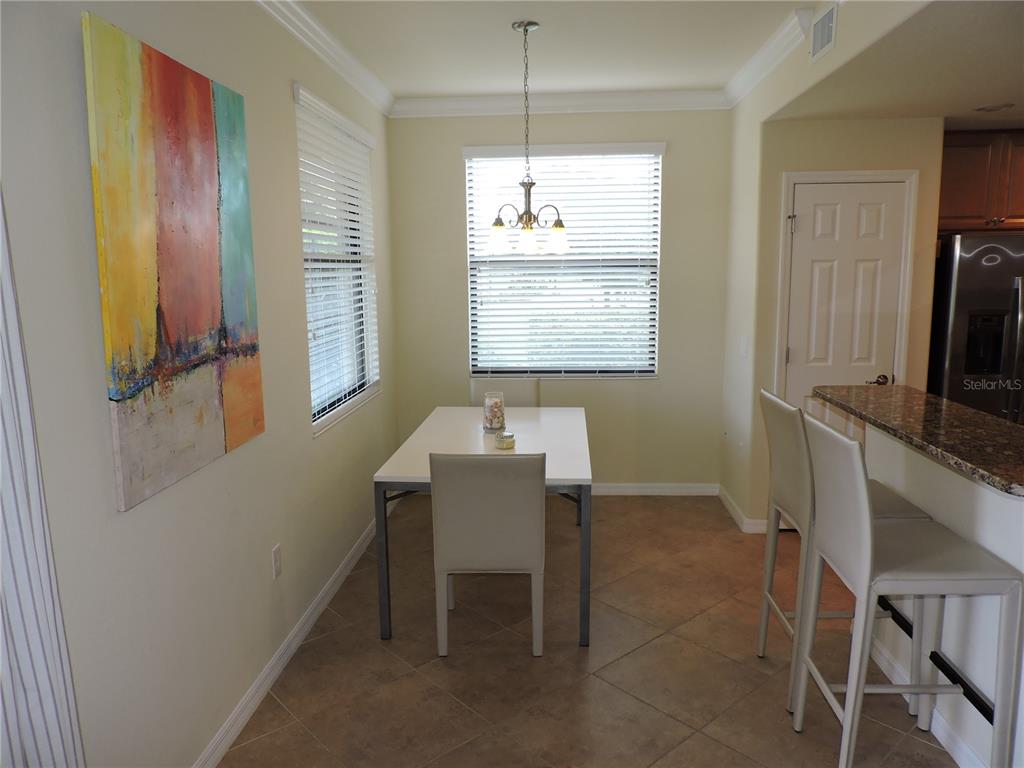 A dining area features a white table, three chairs, a pendant light, and wall art — 20201 RAGAZZA CIRCLE UNIT 102, VENICE, FL