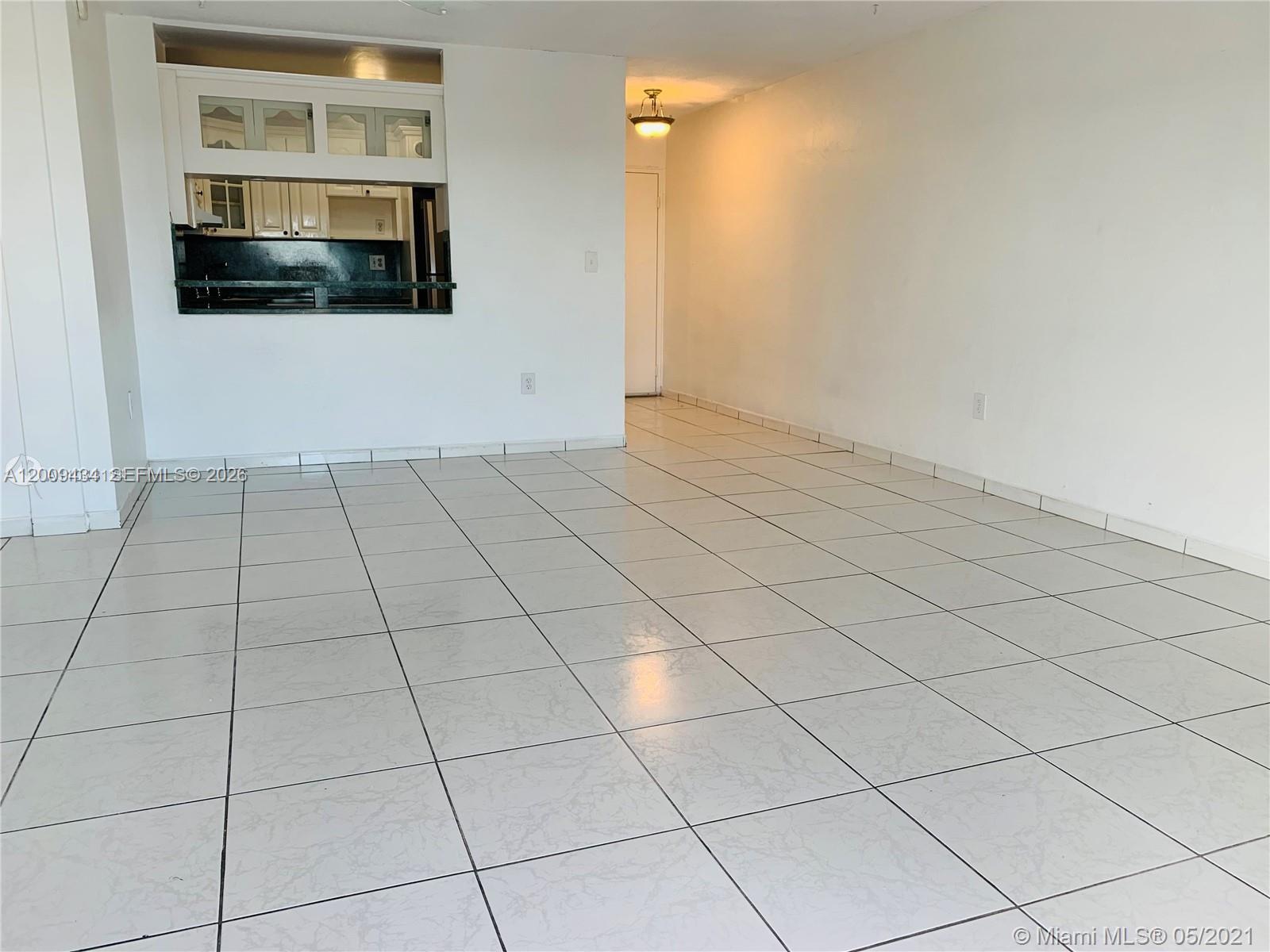 This room features white tiled floors, plain walls, and a kitchen pass-through window — 1325 W 68th St # 514, Hialeah FL 33014, HIALEAH, FL