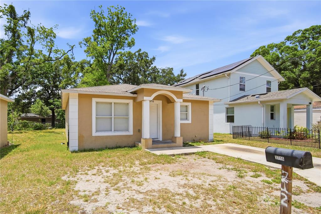 A tan, single-story house with a white-pillared entryway and a black mailbox in the foreground — 3716 N 31ST STREET, TAMPA, FL