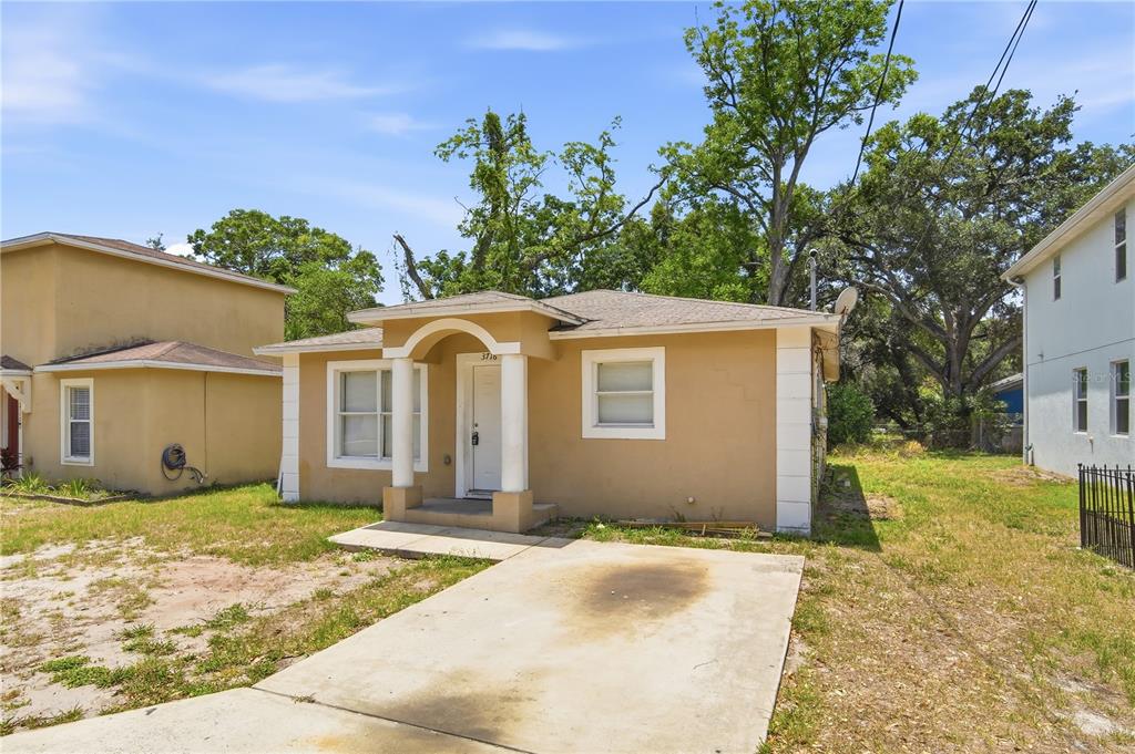 A tan, single-story house with a concrete driveway and a small arched front porch — 3716 N 31ST STREET, TAMPA, FL