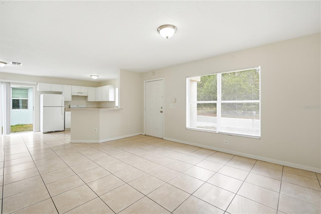 An open-concept living area features light tile flooring, white kitchen cabinets, and a large window — 3716 N 31ST STREET, TAMPA, FL