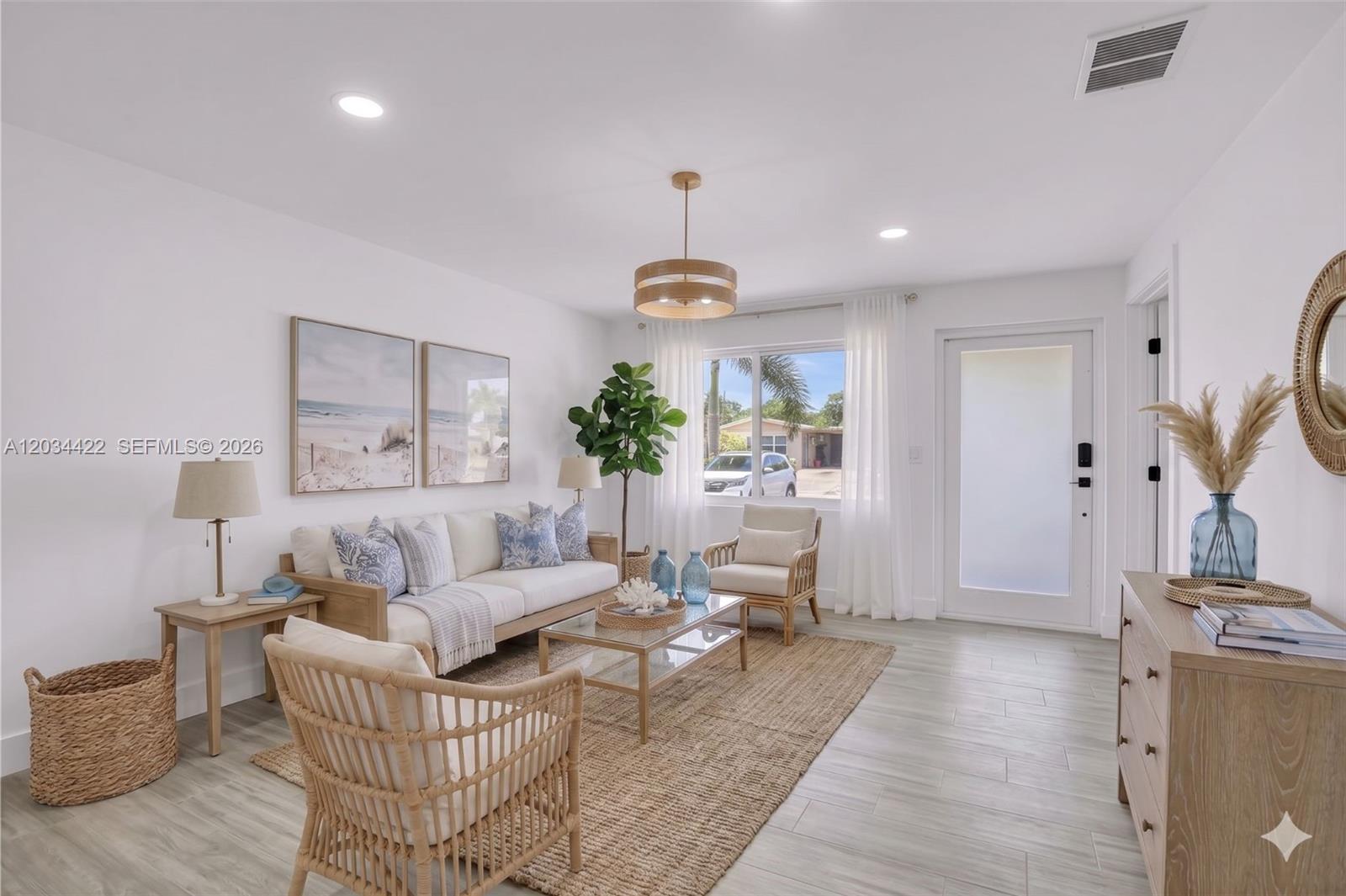A bright living room features a white sofa, rattan chairs, a jute rug, and coastal decor — 311 NW 12th Ave, Delray Beach FL 33444, DELRAY BEACH, FL