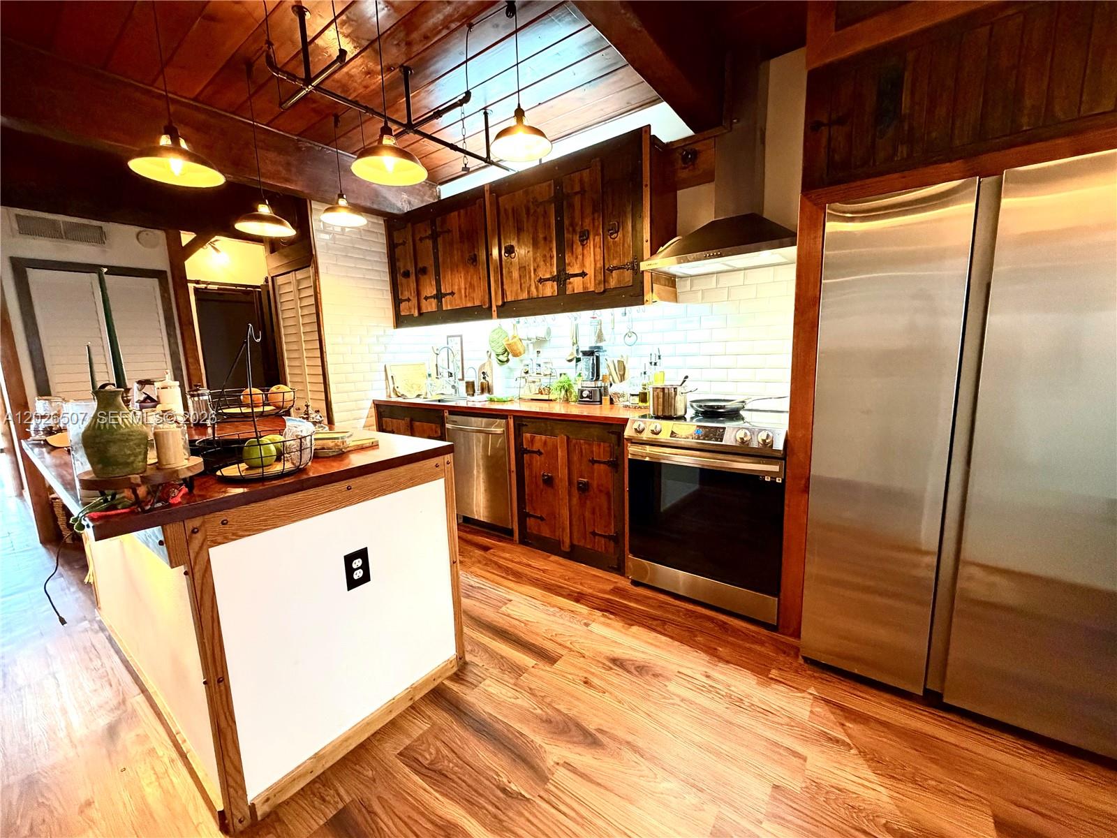 A rustic kitchen features wood cabinets, stainless steel appliances, and a white kitchen island — 19440 NE 26th Ave # 52B, Miami FL 33180, MIAMI, FL