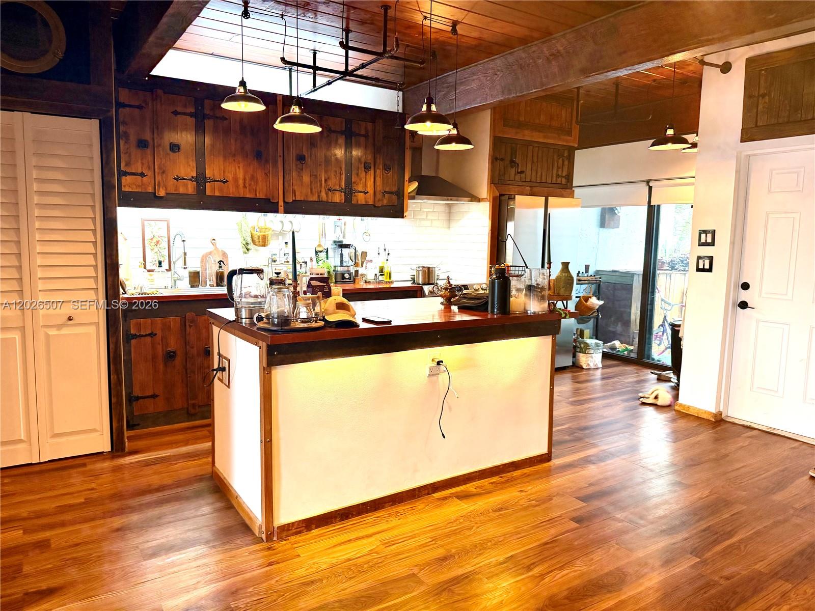 A rustic kitchen features wood cabinets, a central island, and exposed ceiling beams — 19440 NE 26th Ave # 52B, Miami FL 33180, MIAMI, FL