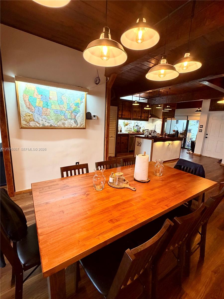 A dining area features a wooden table, dark chairs, and pendant lighting under a beamed ceiling — 19440 NE 26th Ave # 52B, Miami FL 33180, MIAMI, FL