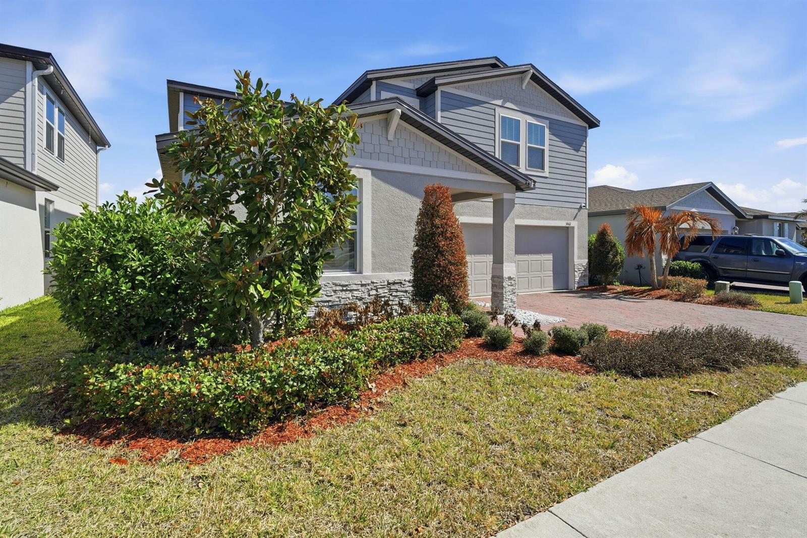 A two-story house with gray siding, stone accents, and a brick driveway under a blue sky — 3061 Cassidy Lane, FL 33844, FL