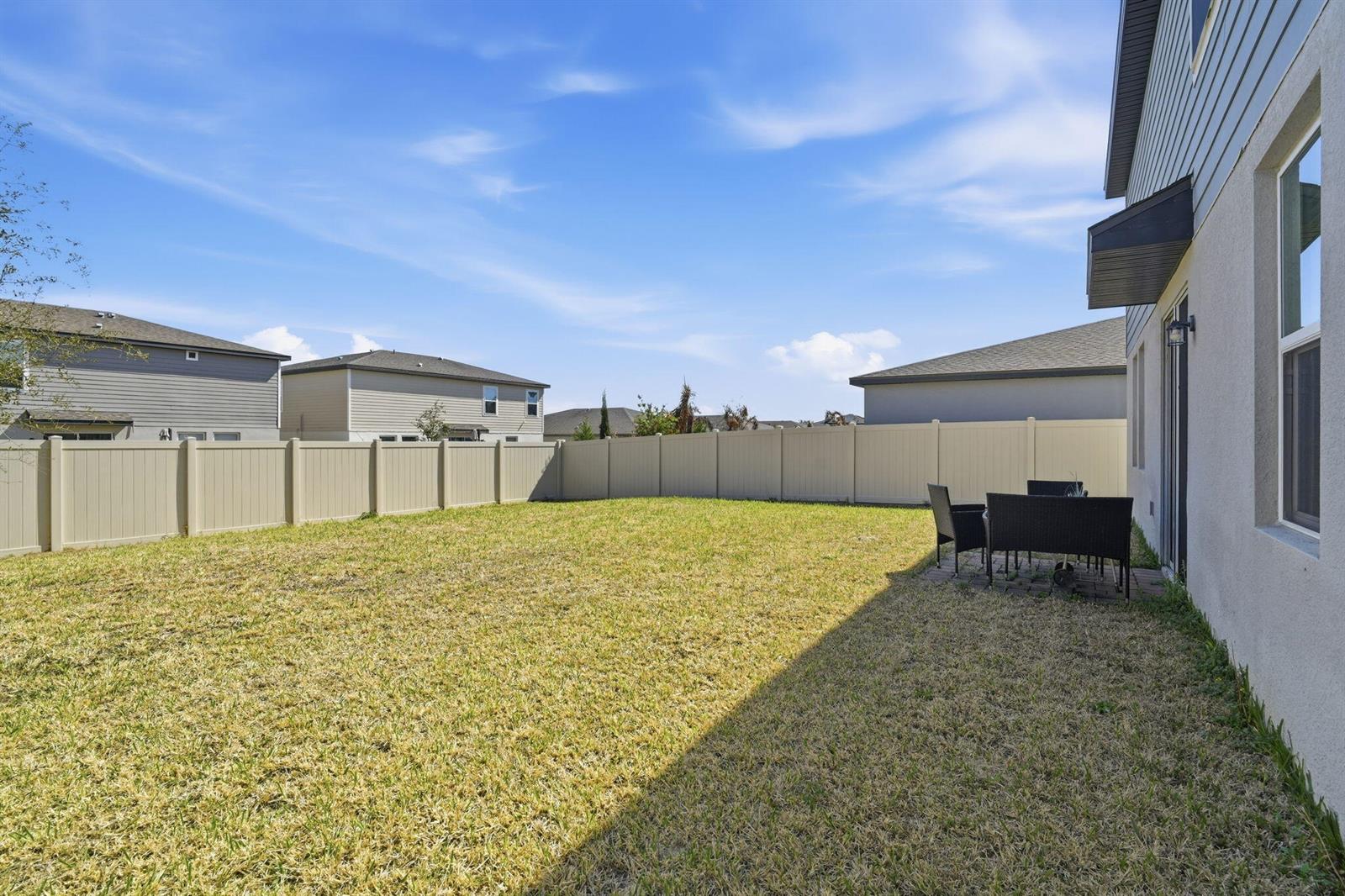 A backyard with a grass lawn, a patio set, and a tan vinyl privacy fence — 3061 Cassidy Lane, FL 33844, FL