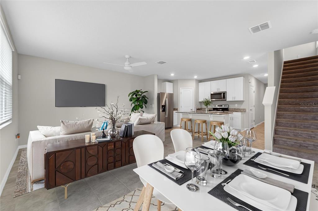 An open-concept living and dining area features a modern kitchen, staircase, and neutral decor — 2710 SCARLET BAY PLACE, BRANDON, FL