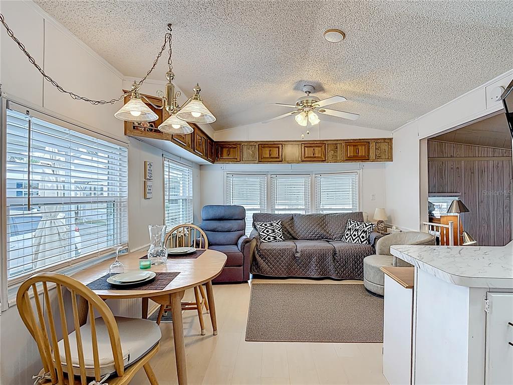 A dining area and living room feature a ceiling fan, wood cabinetry, and white flooring — 9000 US HWY 192 UNIT 763, CLERMONT, FL