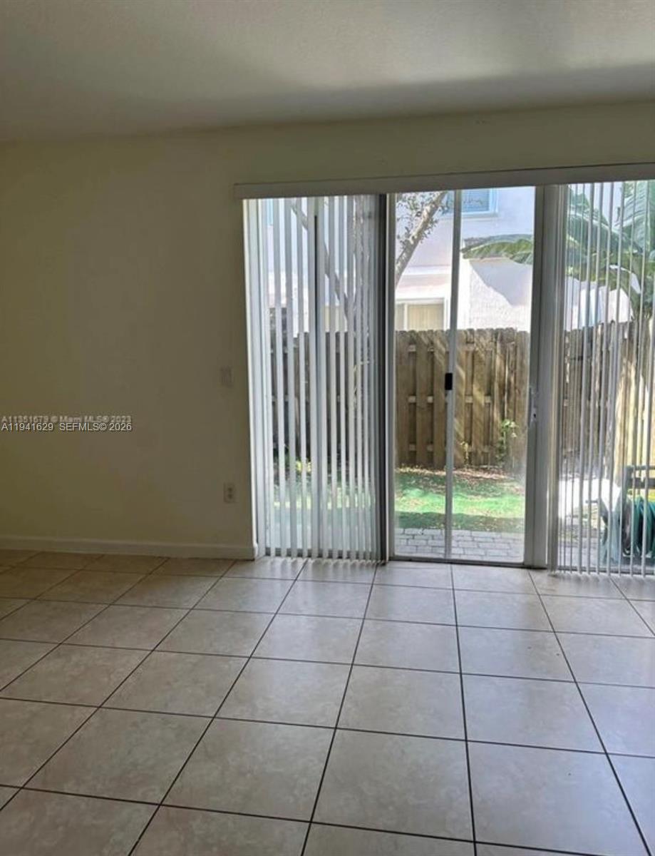 An empty room features light-colored tile flooring and a sliding glass door leading outside — 152 SE 29th Ave # 4, Homestead FL 33033, HOMESTEAD, FL