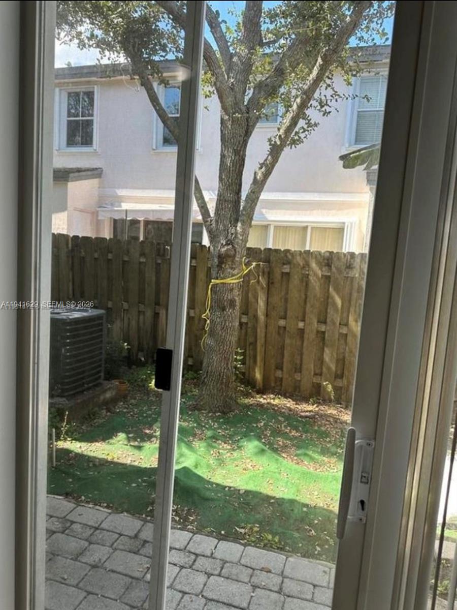 A view through a sliding glass door shows a small backyard with a tree and fence — 152 SE 29th Ave # 4, Homestead FL 33033, HOMESTEAD, FL