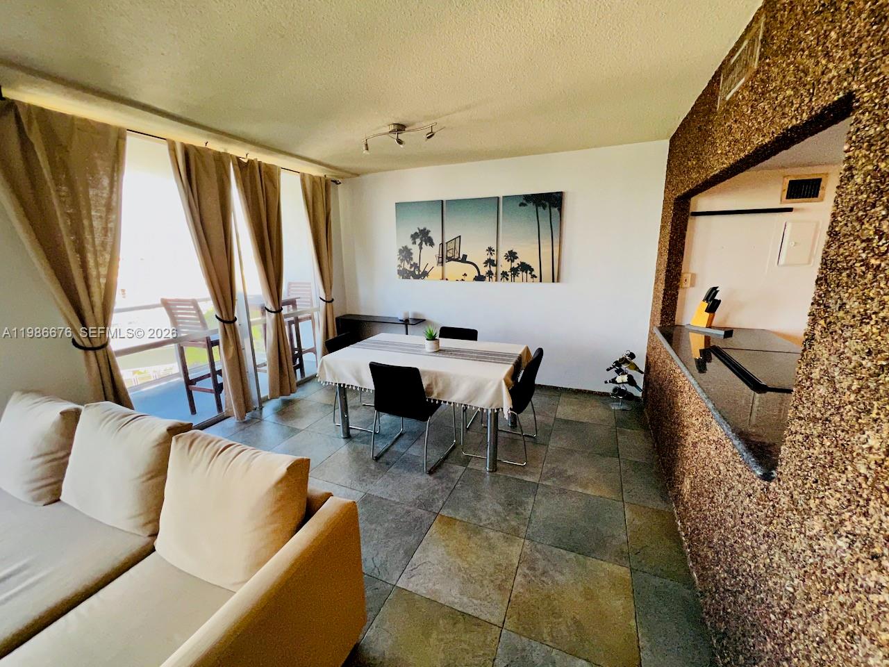 A dining area with a table and chairs sits next to a living room sofa — 900 Bay Dr # 411, Miami Beach FL 33141, MIAMI BEACH, FL