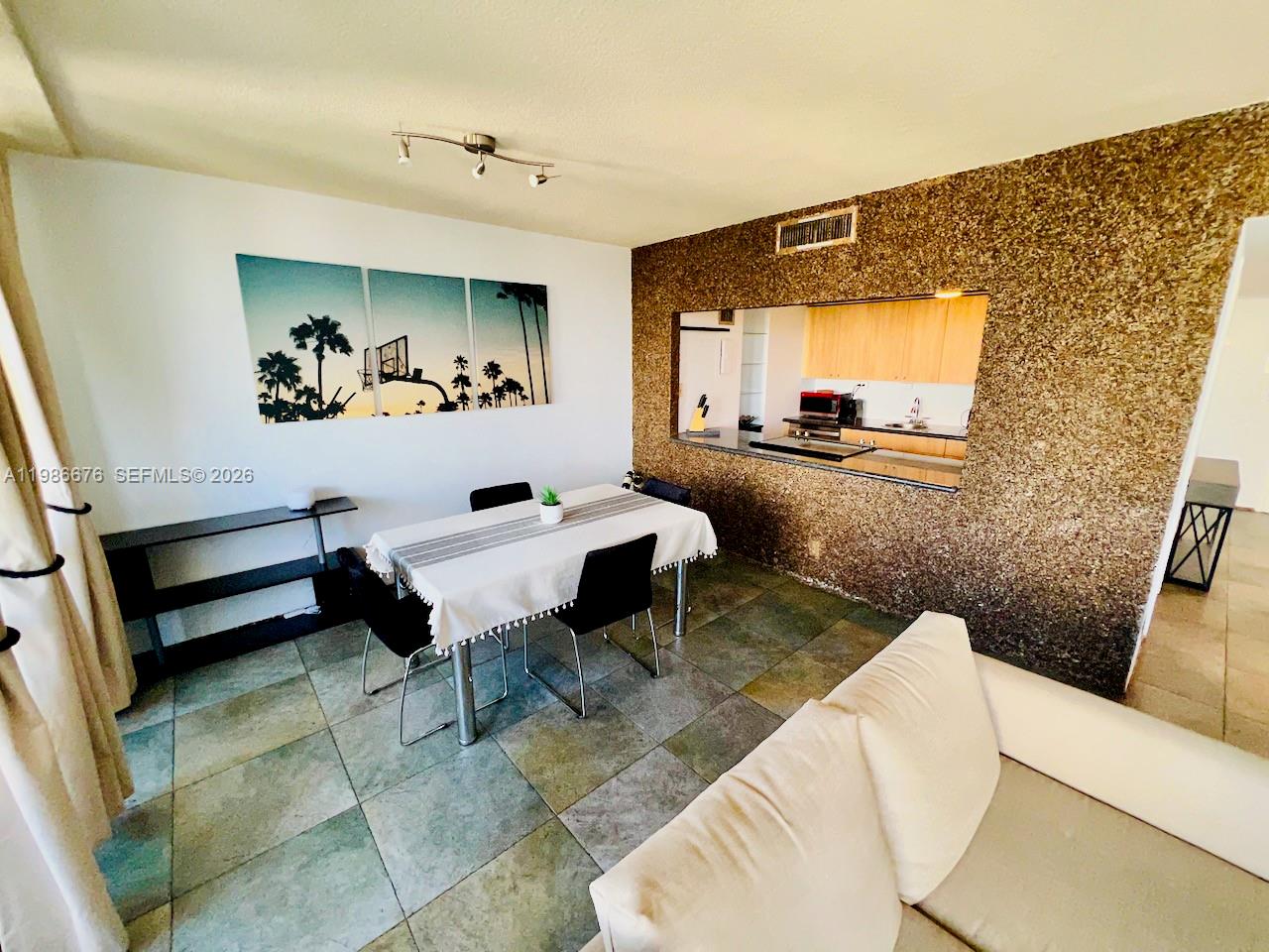 A dining area features a table with chairs, a pass-through window, and textured wall accents — 900 Bay Dr # 411, Miami Beach FL 33141, MIAMI BEACH, FL