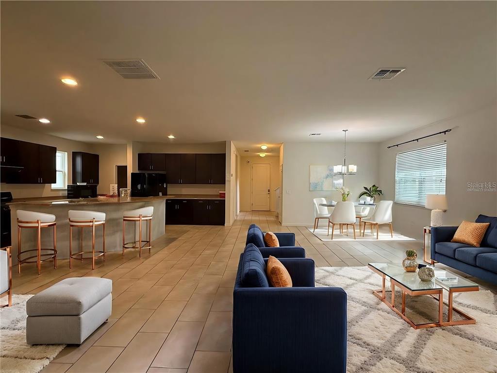 An open-concept living area features a kitchen with dark cabinetry, a dining space, and furniture — 14741 SNOWY EGRET STREET, WINTER GARDEN, FL