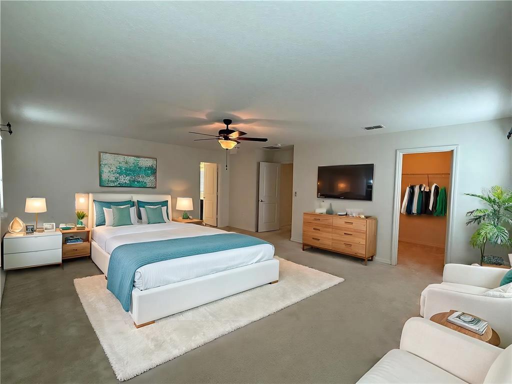 A spacious bedroom features a white bed, a wooden dresser, and a walk-in closet — 14741 SNOWY EGRET STREET, WINTER GARDEN, FL