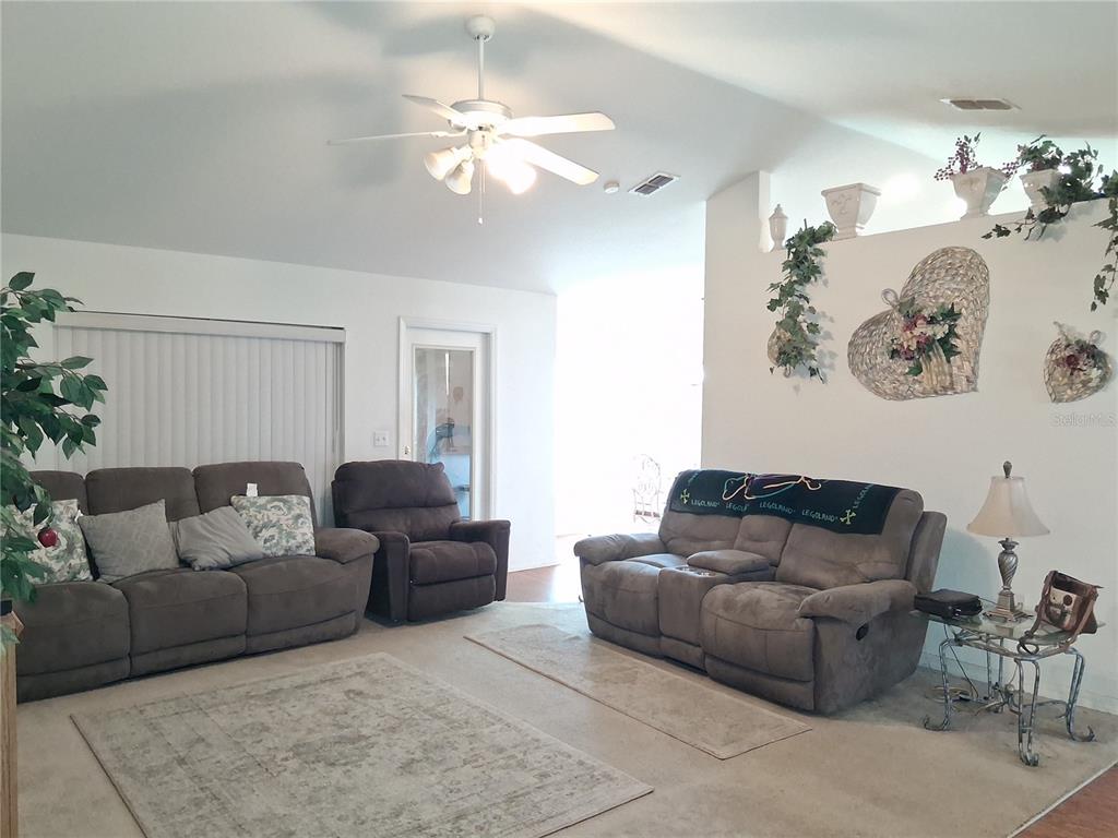 A living room features two brown sofas, a recliner, a ceiling fan, and wall decor — 6759 ASHBURY DRIVE, LAKELAND, FL