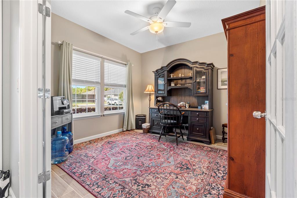 A home office features a dark wood desk, a patterned rug, and a ceiling fan — 7381 SW 78TH TERRACE, OCALA, FL