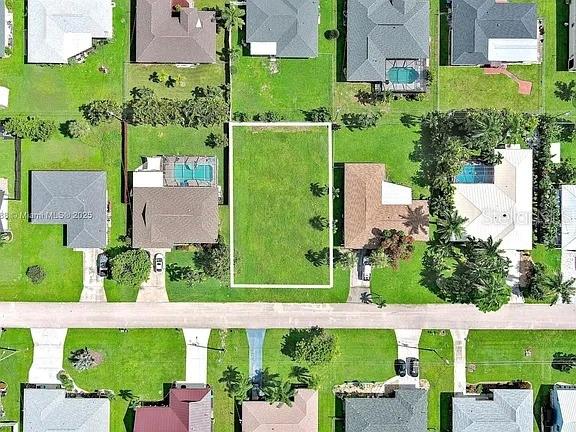 This aerial view shows a vacant residential lot situated between two houses with swimming pools — 225 SW 46TH TERRACE, CAPE CORAL, FL