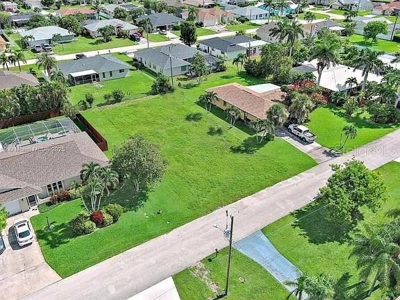 An aerial view shows a vacant grassy lot situated between two residential houses — 225 SW 46TH TERRACE, CAPE CORAL, FL