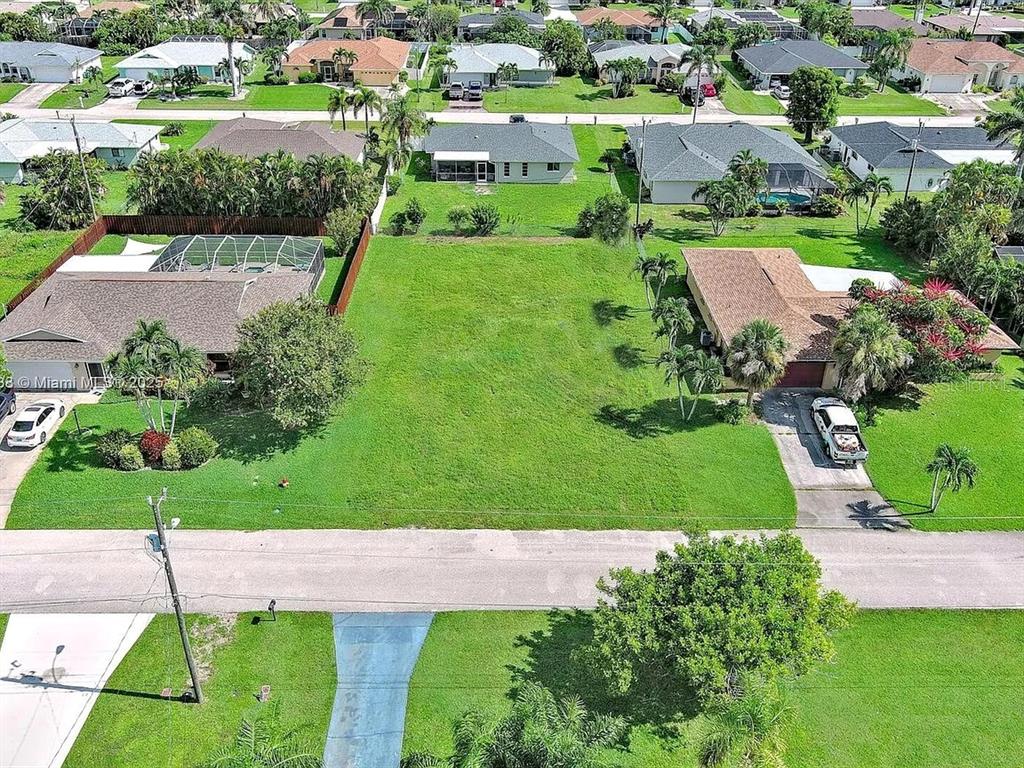 An aerial view shows a vacant residential lot situated between two existing single-family homes — 225 SW 46TH TERRACE, CAPE CORAL, FL