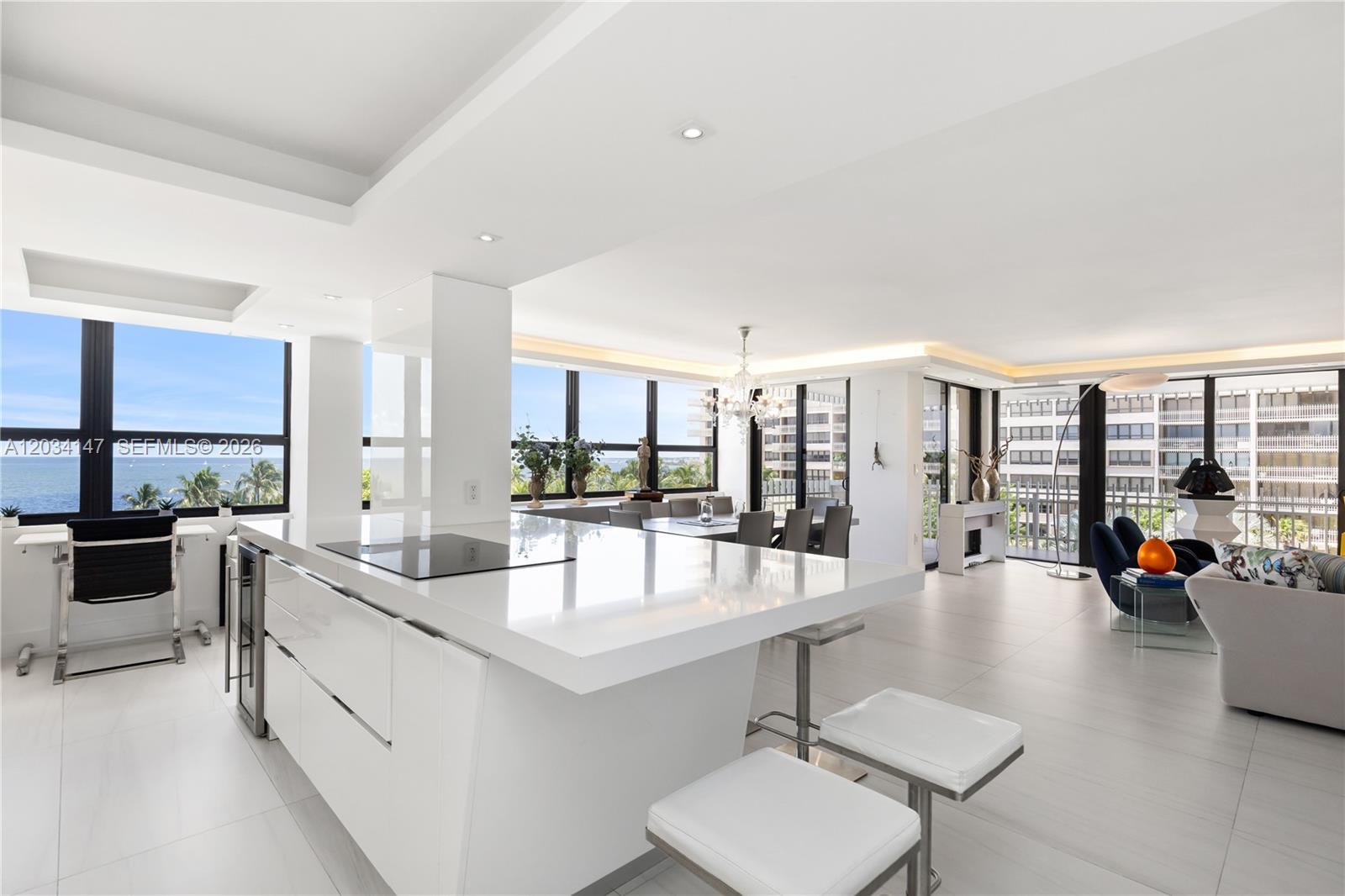 A modern, open-concept kitchen and living area features white cabinetry, quartz countertops, and floor-to-ceiling windows — 3 Grove Isle Dr # C502, Miami FL 33133, MIAMI, FL