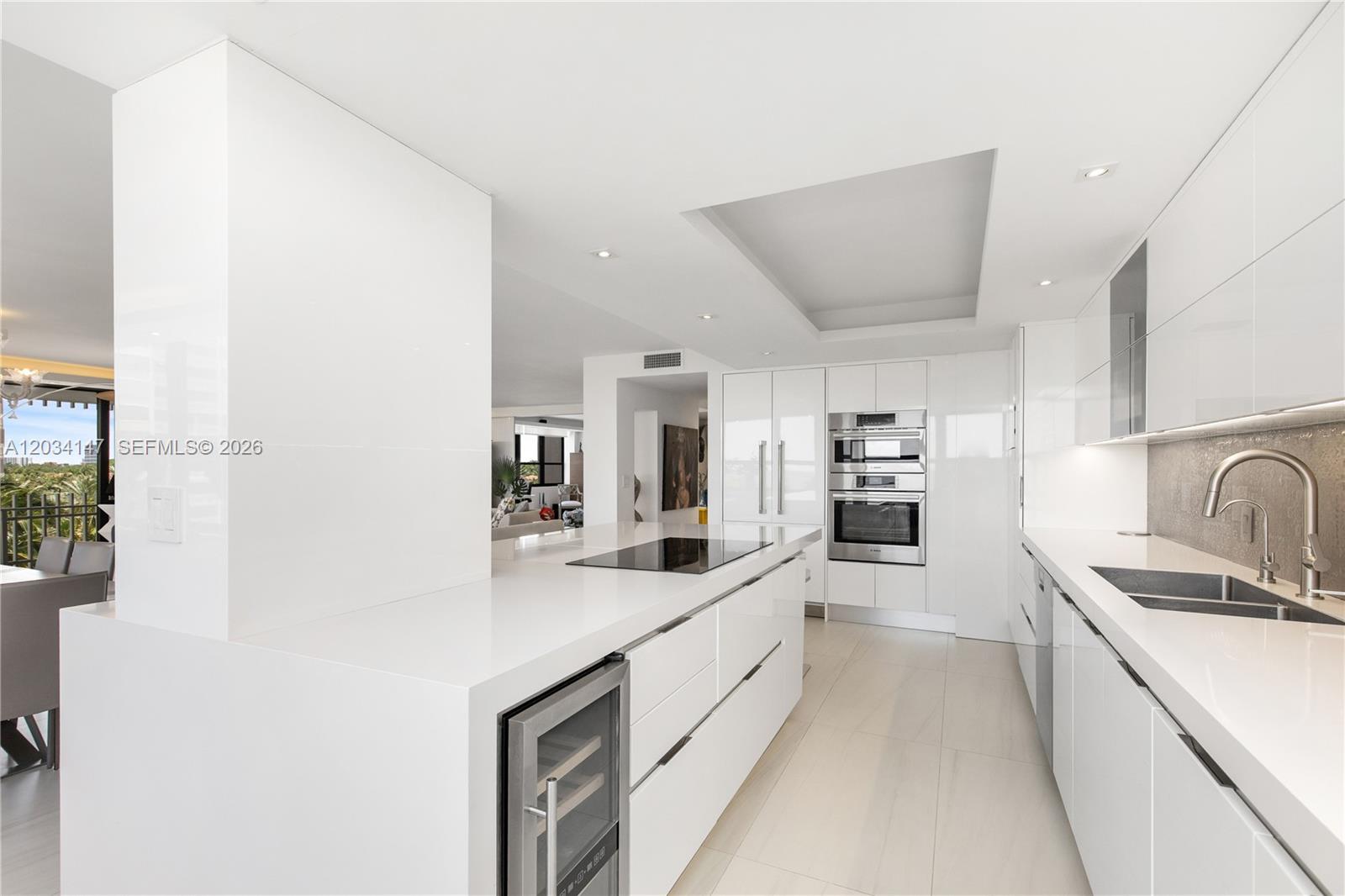 A modern white kitchen features a central island, stainless steel appliances, and sleek cabinetry — 3 Grove Isle Dr # C502, Miami FL 33133, MIAMI, FL