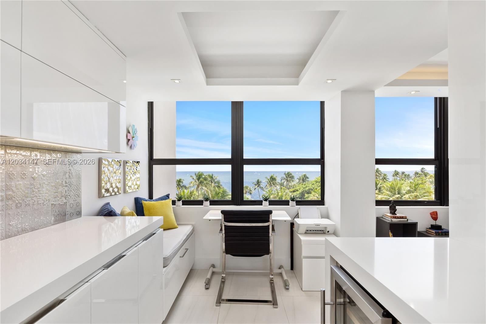 A modern white kitchen features a built-in desk area with large windows overlooking the ocean — 3 Grove Isle Dr # C502, Miami FL 33133, MIAMI, FL