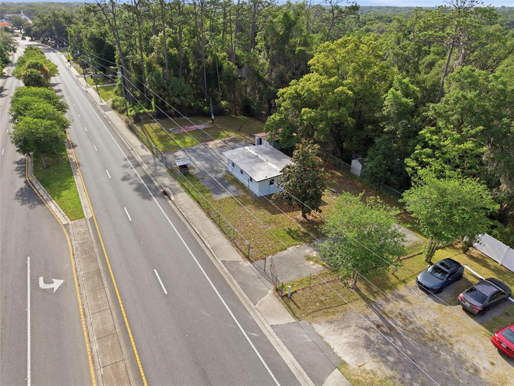 An aerial view shows a small light-blue house situated next to a multi-lane road — 320 HIGHWAY 466, LADY LAKE, FL