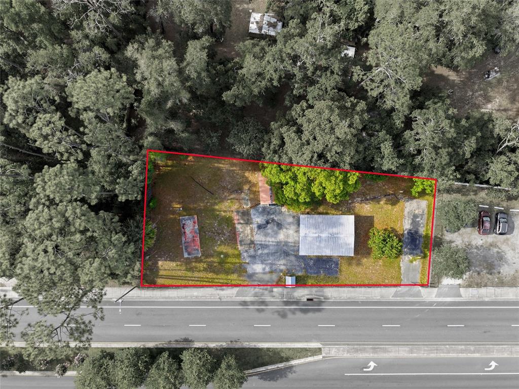 An aerial view shows a rectangular lot with a small building, pavement, and surrounding trees — 320 HIGHWAY 466, LADY LAKE, FL