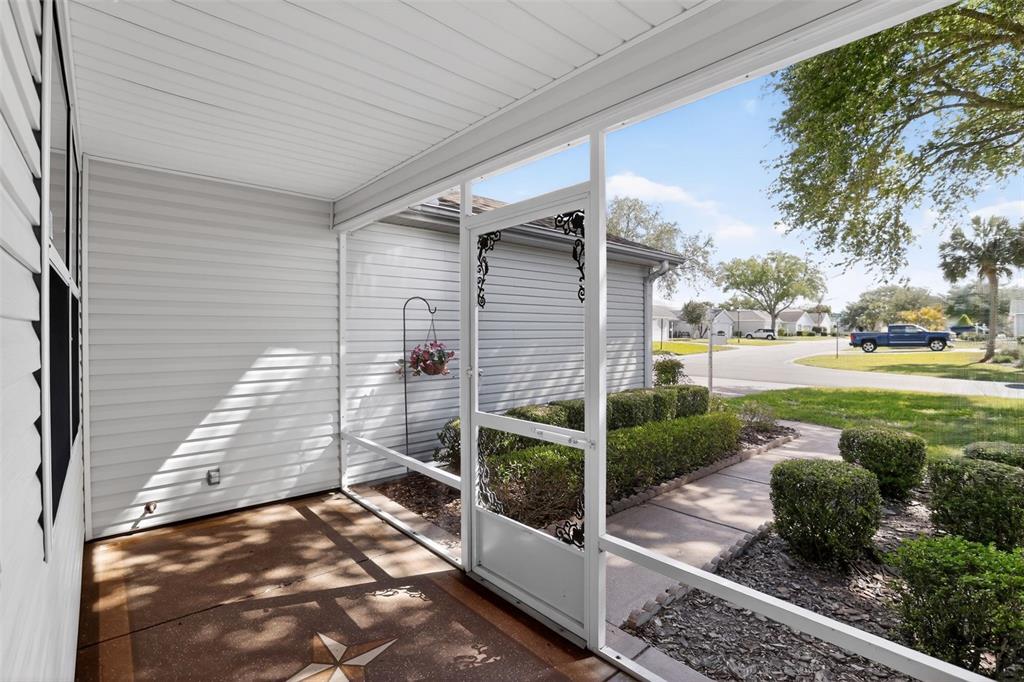 A screened-in porch features a concrete floor, white siding, and a view of the neighborhood — 728 RIVERA ROAD, THE VILLAGES, FL