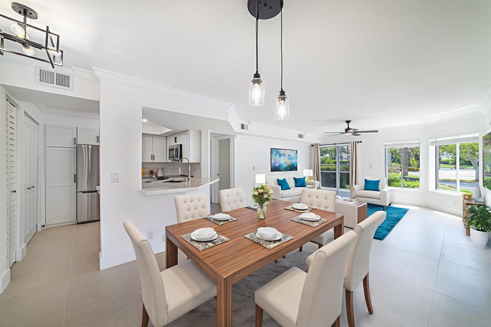 A dining area with a wooden table and chairs opens into a bright living room — 815 W Boynton Beach Boulevard # 106, Boynton Beach FL 33426, BOYNTON BEACH, FL
