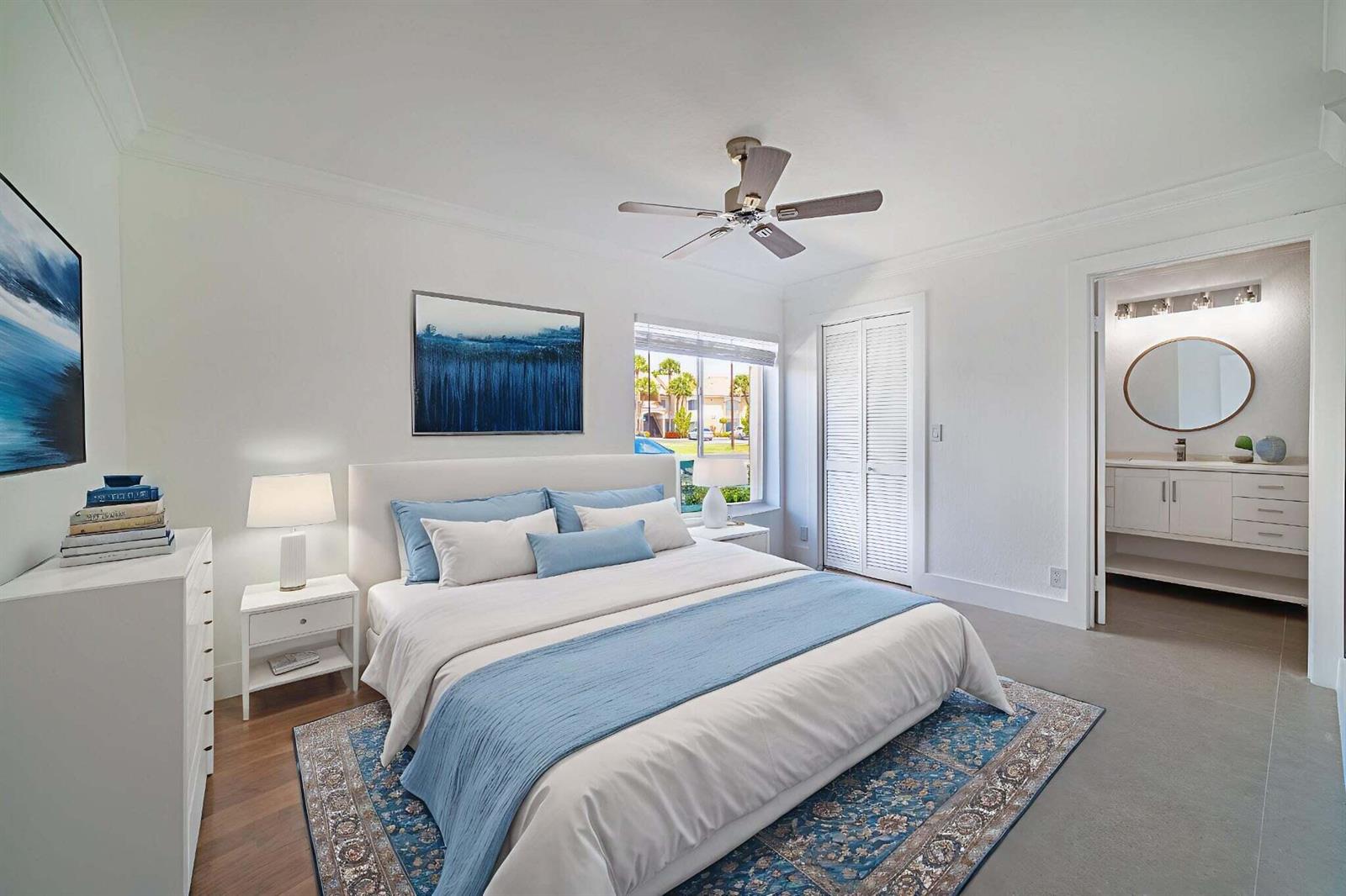 A bedroom features a white bed with blue accents, a rug, and an attached bathroom — 815 W Boynton Beach Boulevard # 106, Boynton Beach FL 33426, BOYNTON BEACH, FL