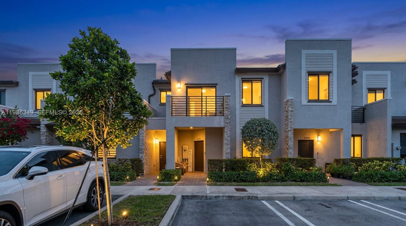 A modern two-story townhouse exterior with a balcony, stone accents, and a parked white car — 21068 NE 8th Ave, Miami FL 33179, MIAMI, FL