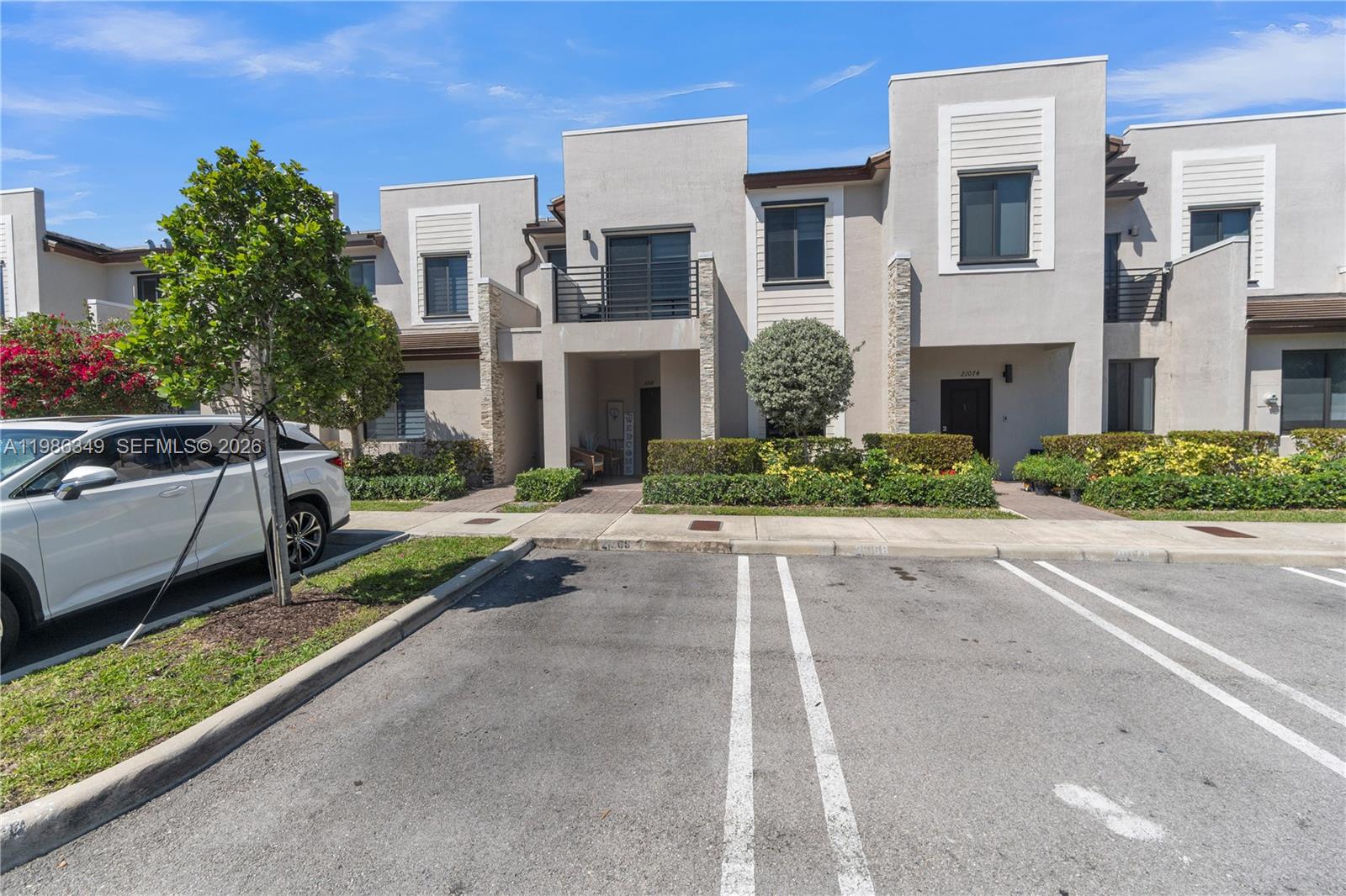 A white SUV is parked in front of a multi-story townhouse complex with modern architecture — 21068 NE 8th Ave, Miami FL 33179, MIAMI, FL