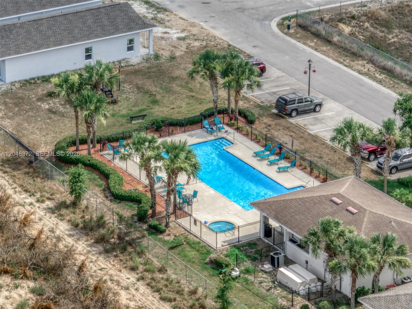 An aerial view shows a rectangular swimming pool and hot tub enclosed by a black fence — 1428 Las Villas Blvd, Sebring FL 33870, SEBRING, FL