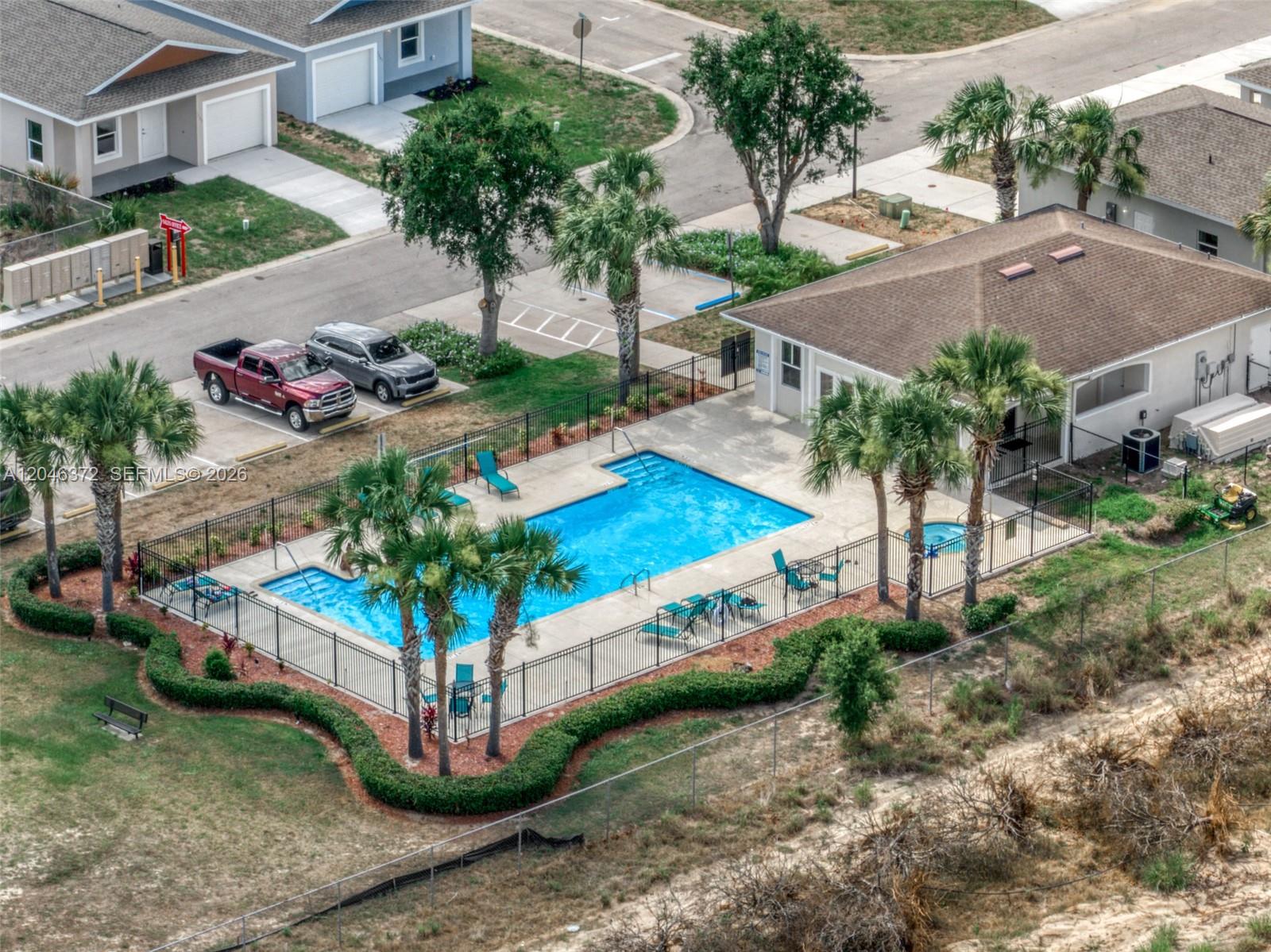 An aerial view shows a swimming pool with a surrounding fence and adjacent clubhouse — 1428 Las Villas Blvd, Sebring FL 33870, SEBRING, FL