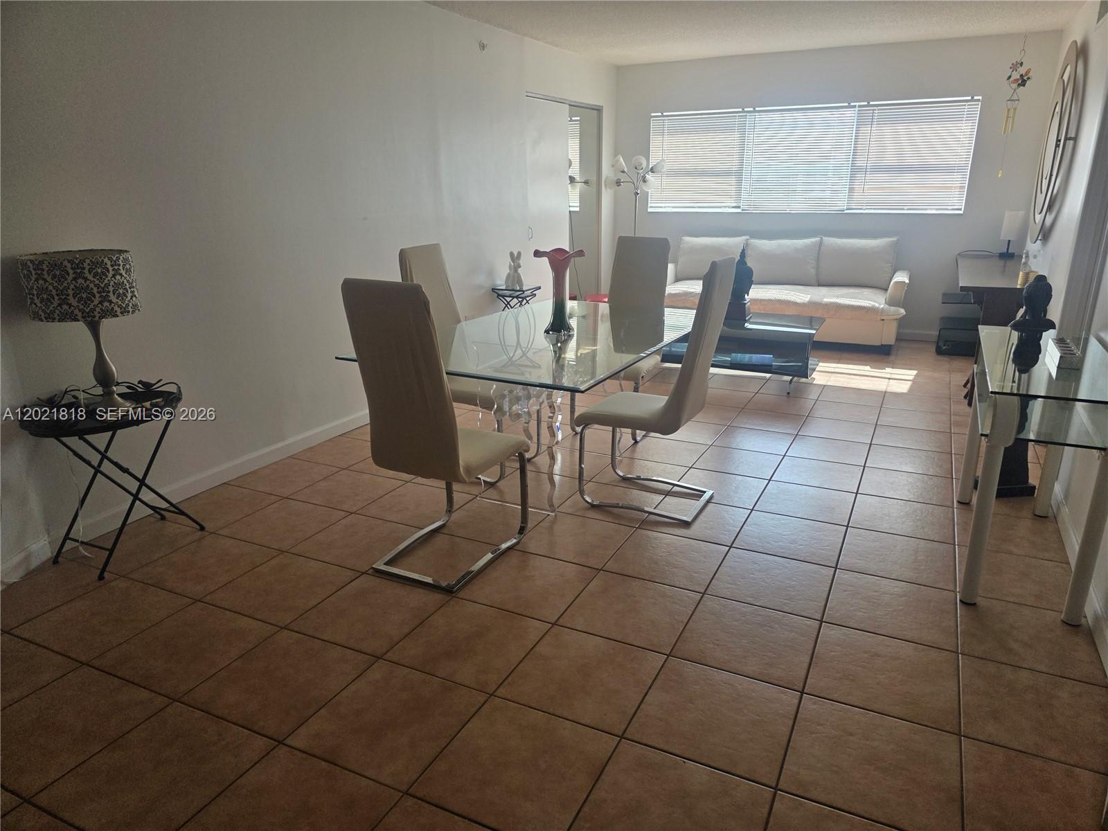 A dining area with a glass table and chairs sits adjacent to a living room — 1881 Washington Ave # 6H, Miami Beach FL 33139, MIAMI BEACH, FL