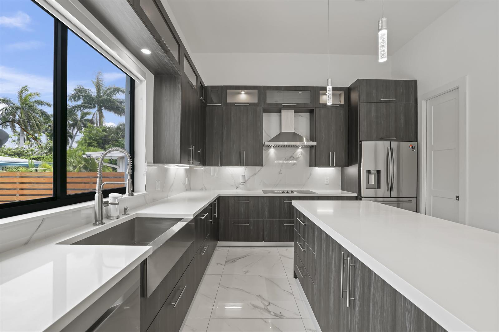 A modern kitchen features dark wood cabinetry, white quartz countertops, and a large farmhouse sink — 2620 SE 6th Street, Pompano Beach FL 33062, POMPANO BEACH, FL