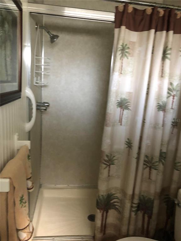 A shower stall with a palm tree patterned curtain and a wall-mounted shower head — 7545 FIRST CIRCLE DRIVE, BROOKSVILLE, FL