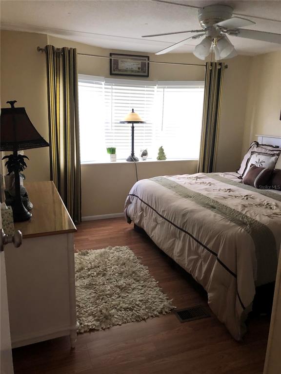 A bedroom features a bed, a dresser, a window with blinds, and a ceiling fan — 7545 FIRST CIRCLE DRIVE, BROOKSVILLE, FL